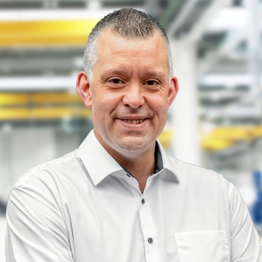 Portrait von Alexander Siepe, Ansprechpartner bei DOLL, mit kurzen schwarzen Haaren, weißem Hemd und schwarzem Sakko